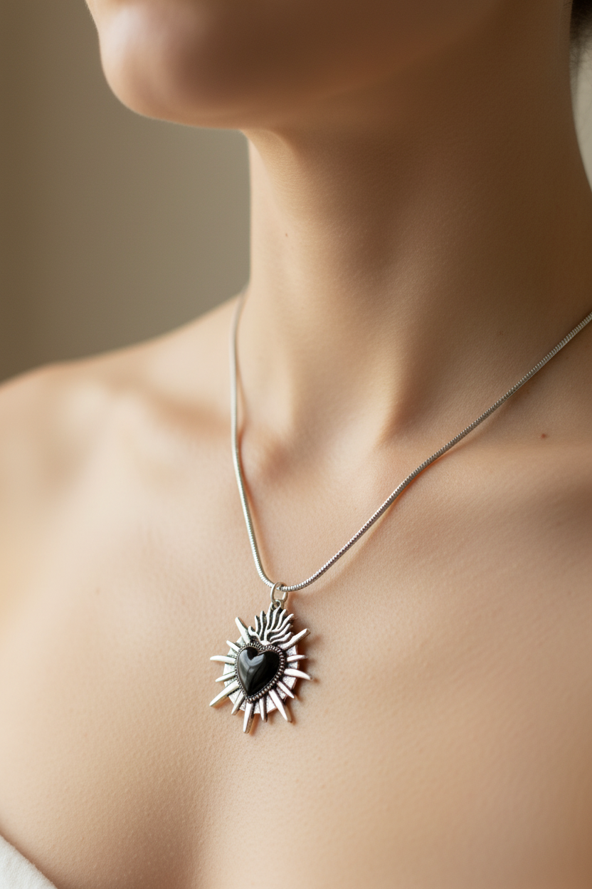 A silver-toned chain necklace with a black stone spike heart pendant displayed on a model