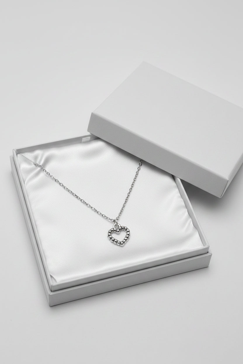 Silver necklace with a heart-shaped pendant in a large white gift box.