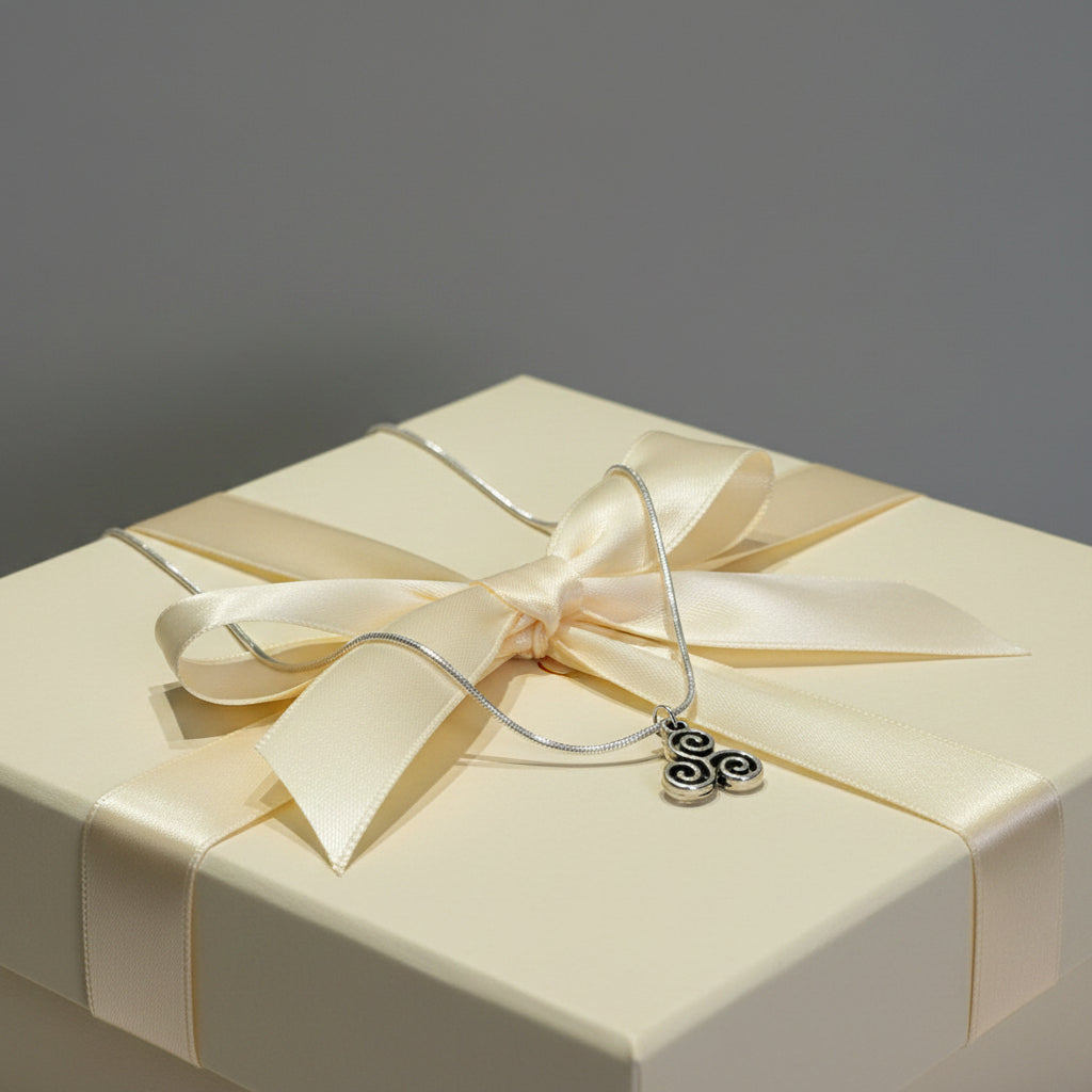 Silver necklace with a triskele pendant on a large beige gift box
