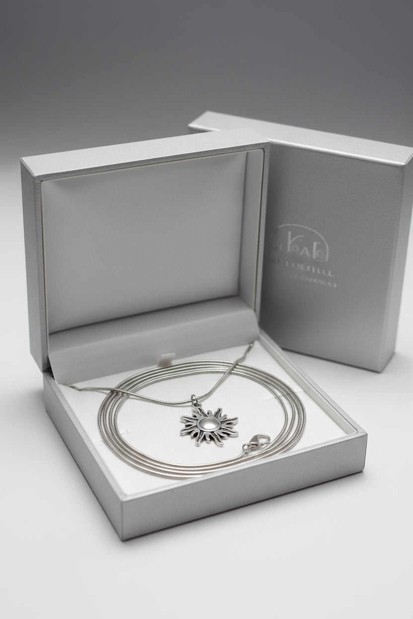 A silver sun pendant necklace displayed in a white gift box.