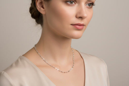 Woman wearing a silver necklace against a neutral background