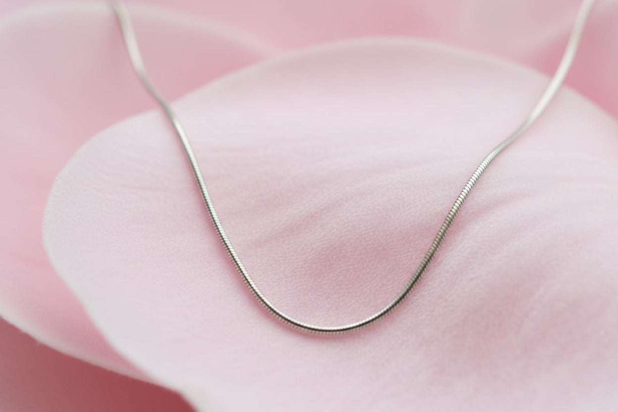 Silver necklace on a pink fabric background
