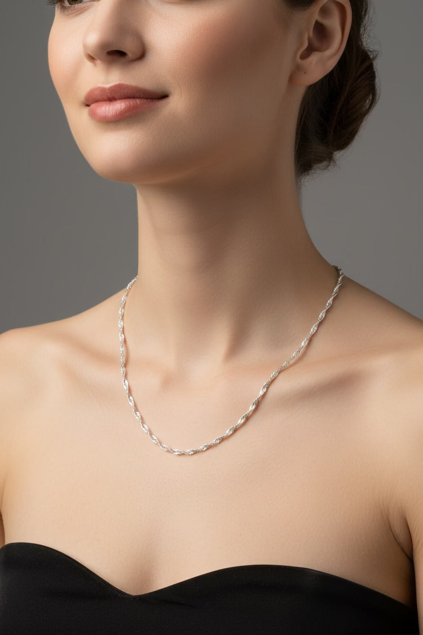 Close-up of a woman wearing a delicate silver necklace against a neutral background