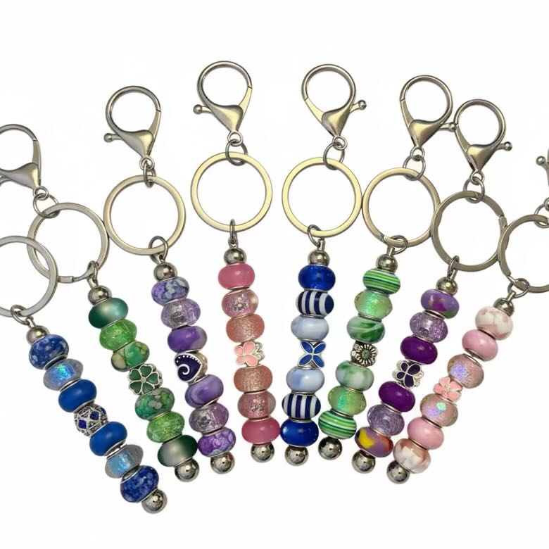 A group of silver chain colourful keyrings with various coloured beads, on a plain white background.