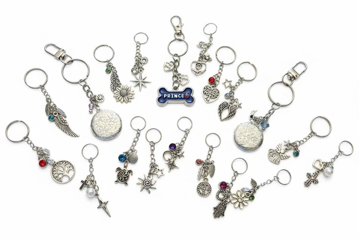 A set of 18 silver-toned keyring/keyrings with various charms, including stars, moons, crosses, flowers, and a blue enamel 'PRINCE' bone, arranged on a plain white background.