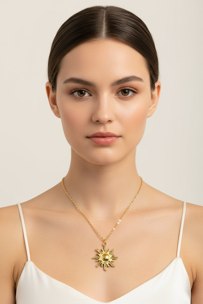 An adjustable gold-toned sunburst pendant necklace displayed on a model, wearing a white op.