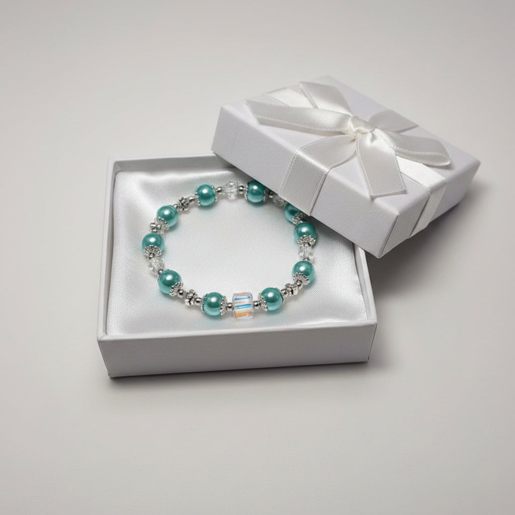 A beaded stretch bracelet featuring light blue-aqua glass pearl beads, silver-toned spacer beads, and a central iridescent square bead, displayed on a neutral light gray background.