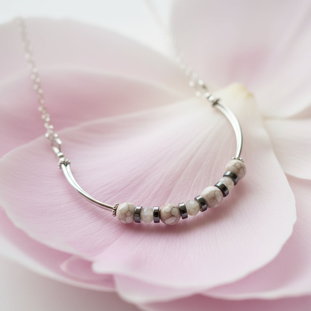 Silver necklace with beads on a pink flower petal