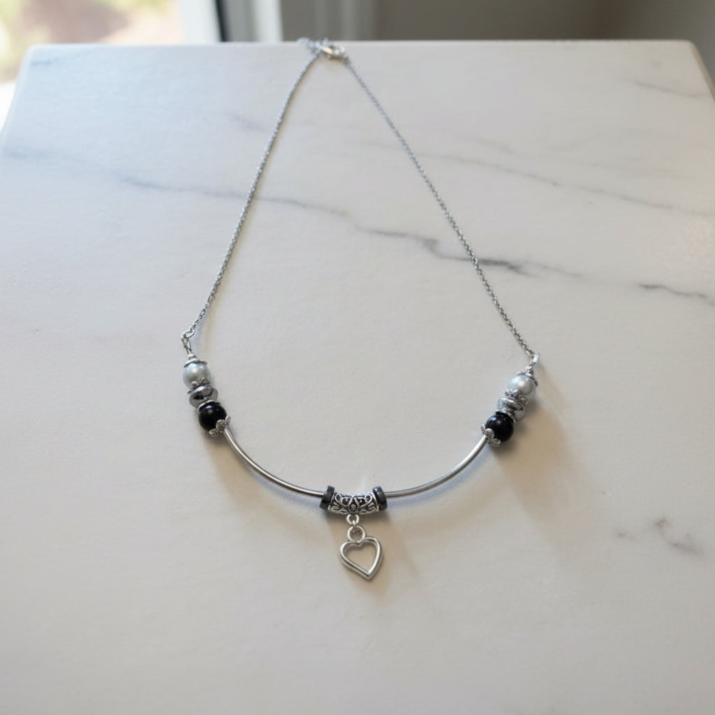 Necklace with heart pendant and beads on a white marbled background