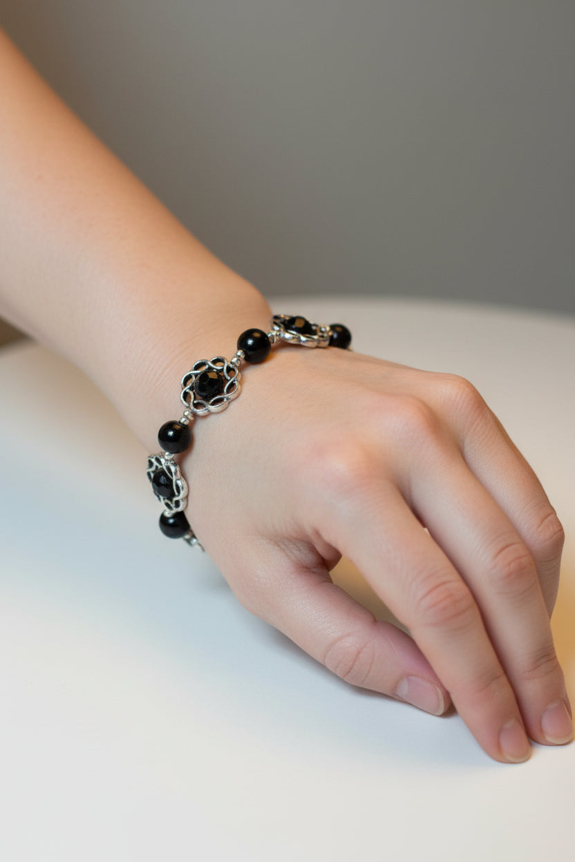 Bracelet with black pearls encased in metal charms on a model