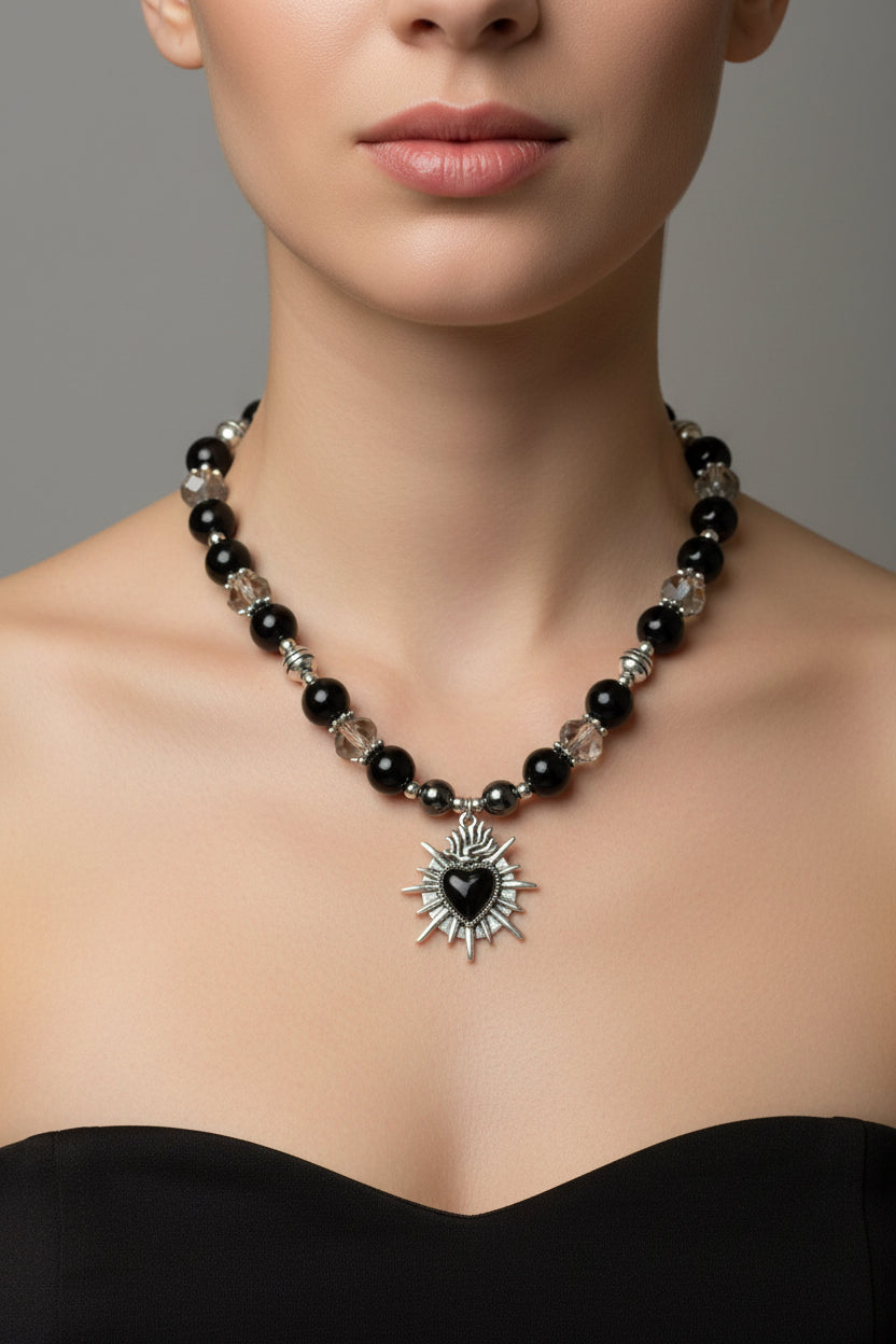 Necklace with black beads and a silver black heart pendant on a model