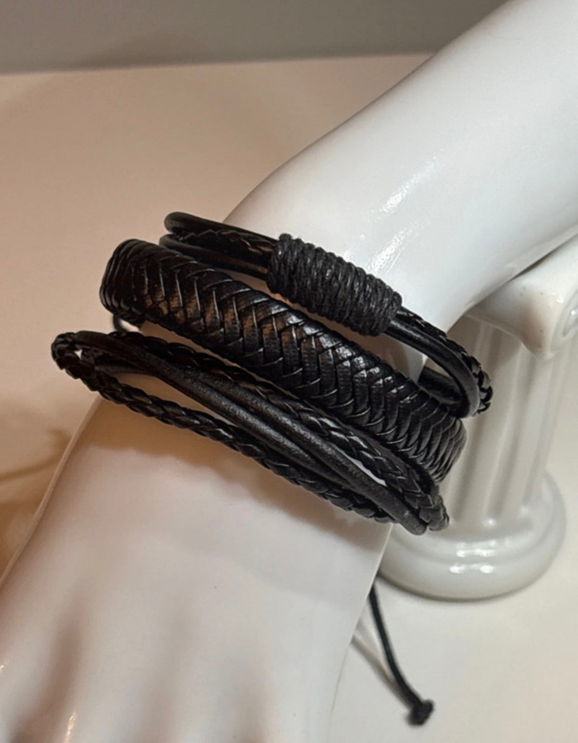 Black braided bracelet on a mannequin arm against a neutral background