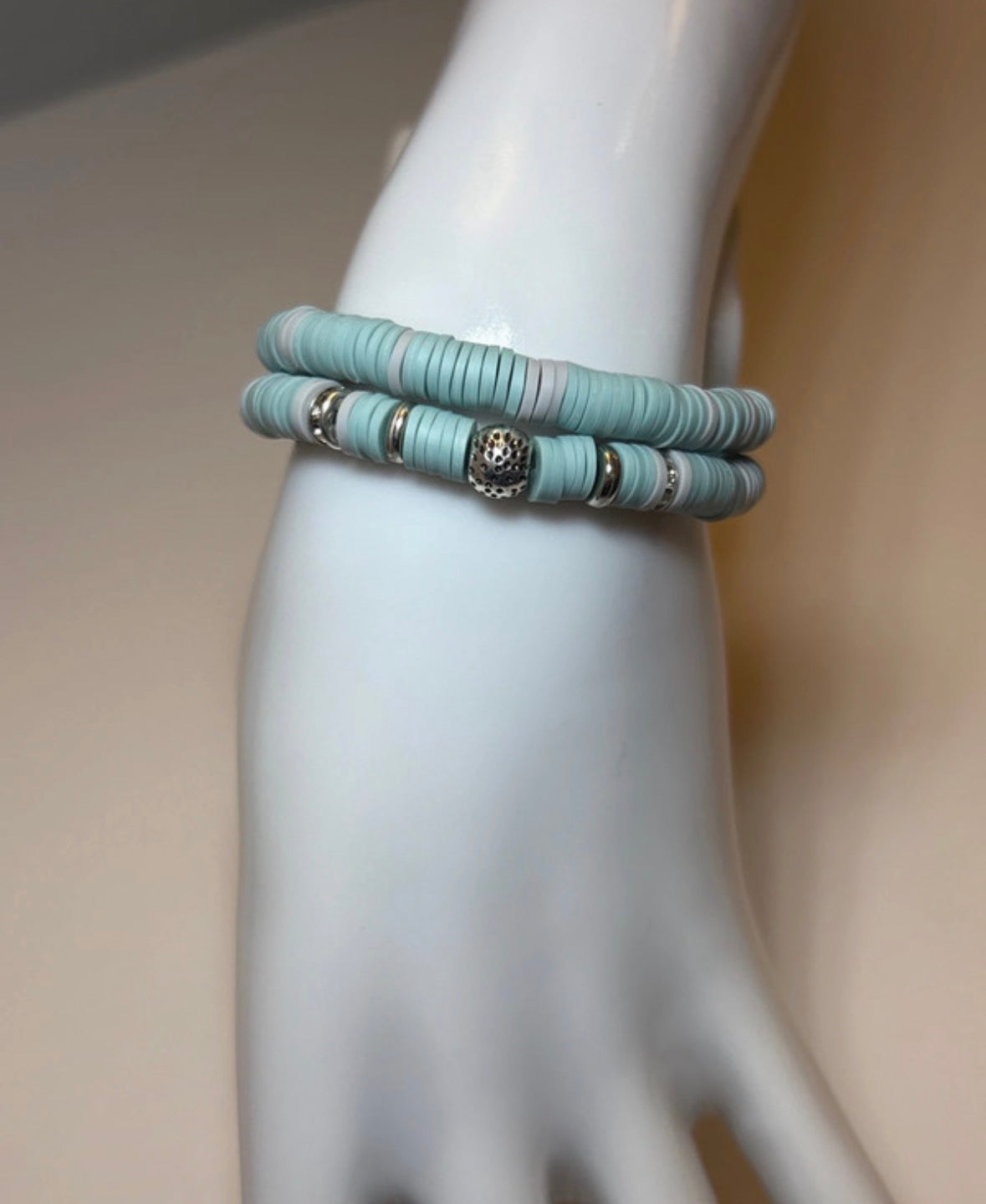 Blue bracelet on a mannequin wrist with a plain background