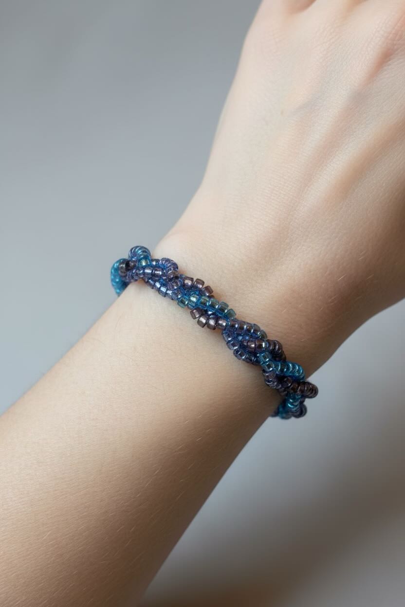 Blue beaded bracelet on a wrist against a neutral background