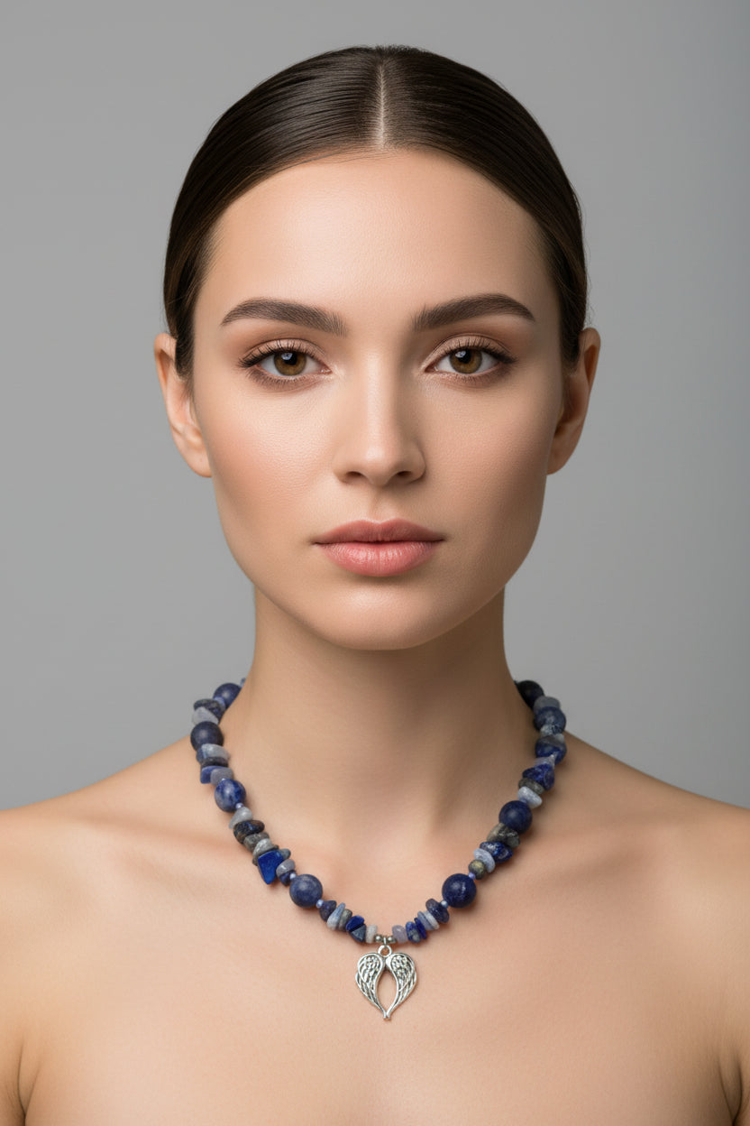 Woman wearing a blue beaded necklace with a silver pendant against a gray background