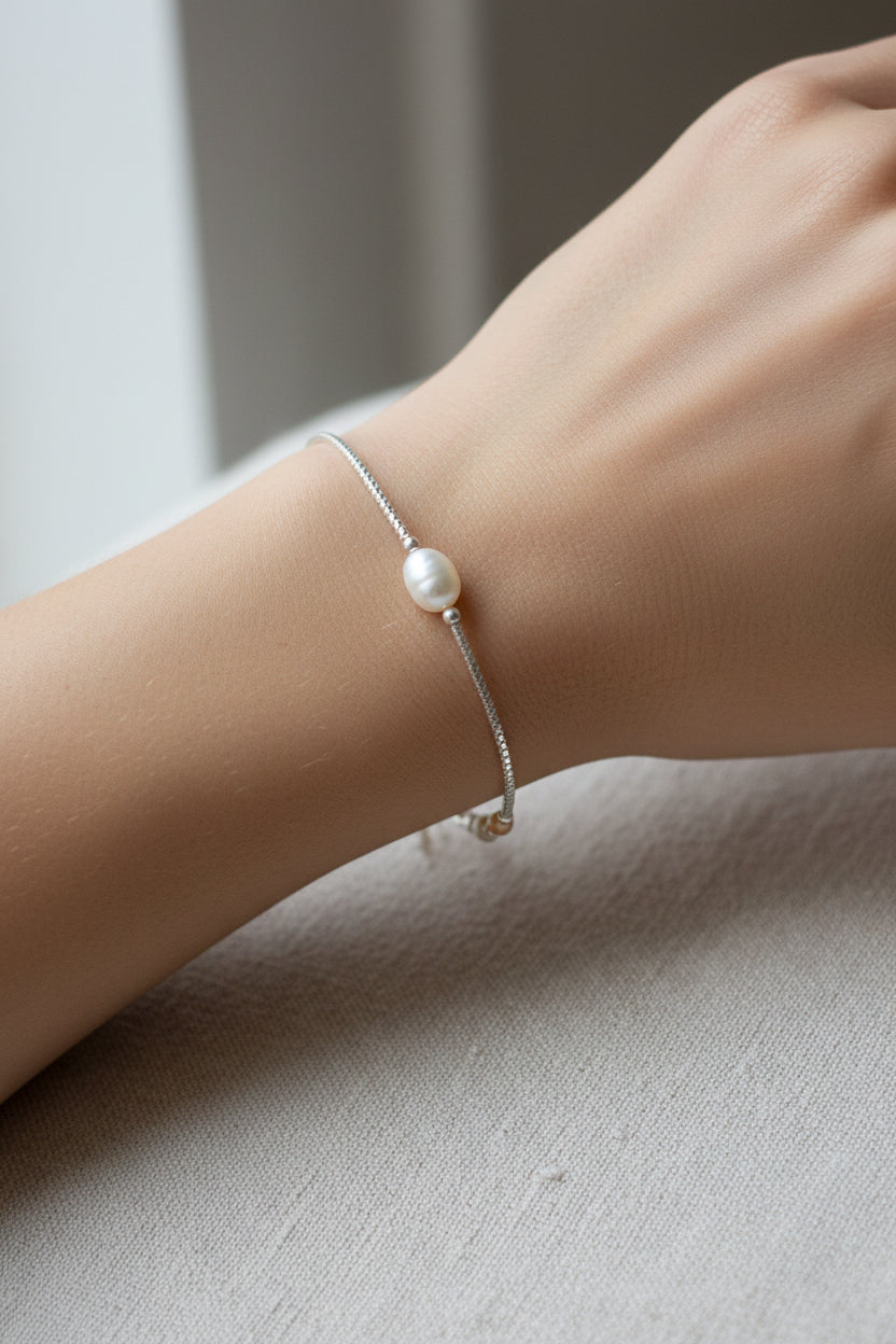 Pearl bracelet on a model's arm against a neutral background