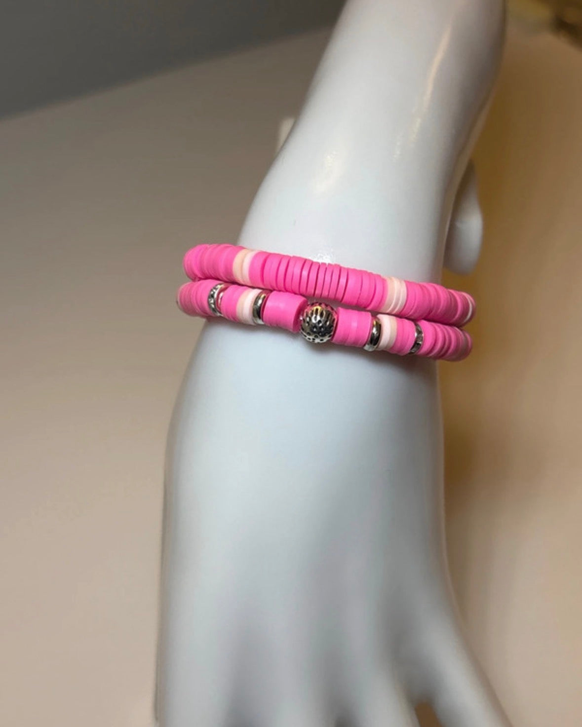 Pink beaded bracelet on a mannequin arm with a neutral background