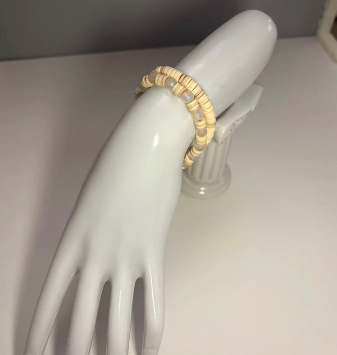 Cream bracelet set on a white mannequin hand against a neutral background