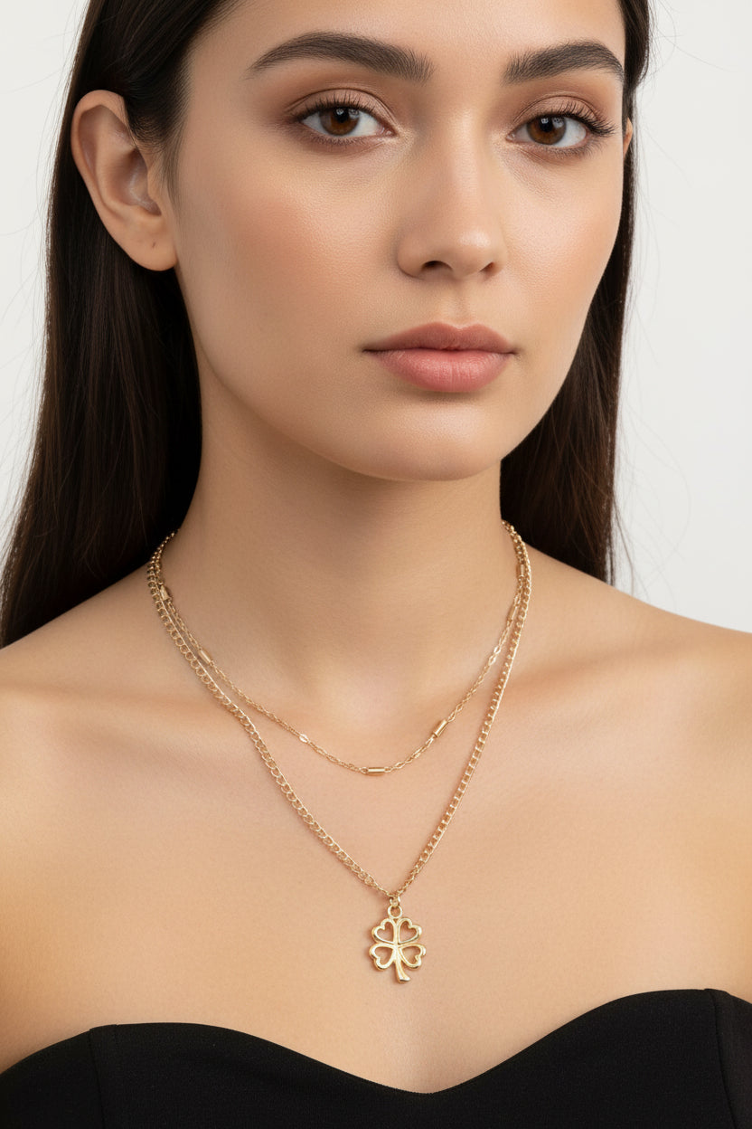 A silver-tone chain necklace set with a four-leaf clover pendant on a model
