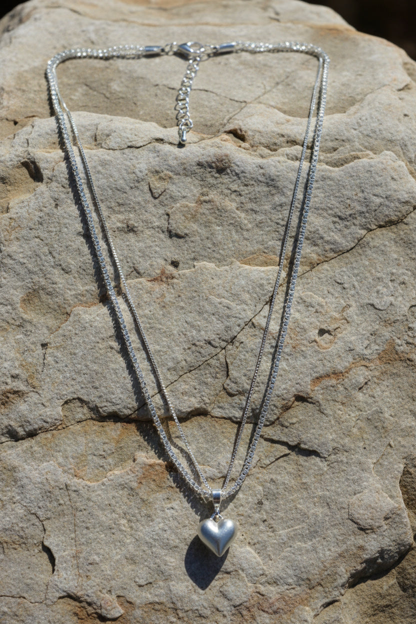 Silver necklace set with a heart pendant on a large stone
