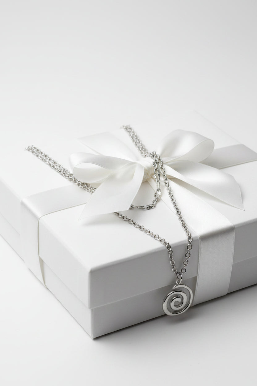 Silver chain necklace with a spiral pendant on a large gift box