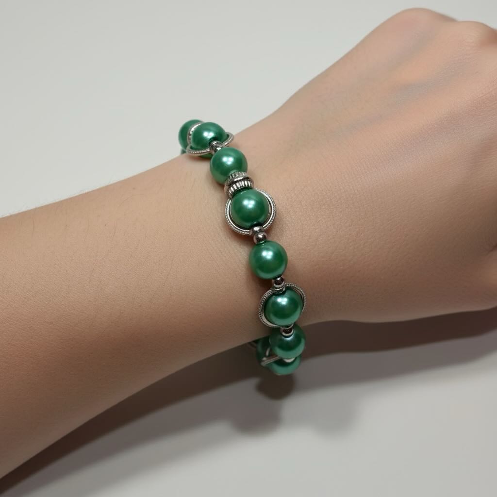 A sea green pearl bracelet with silver-toned spacer details worn on a person's wrist against a plain light background.
