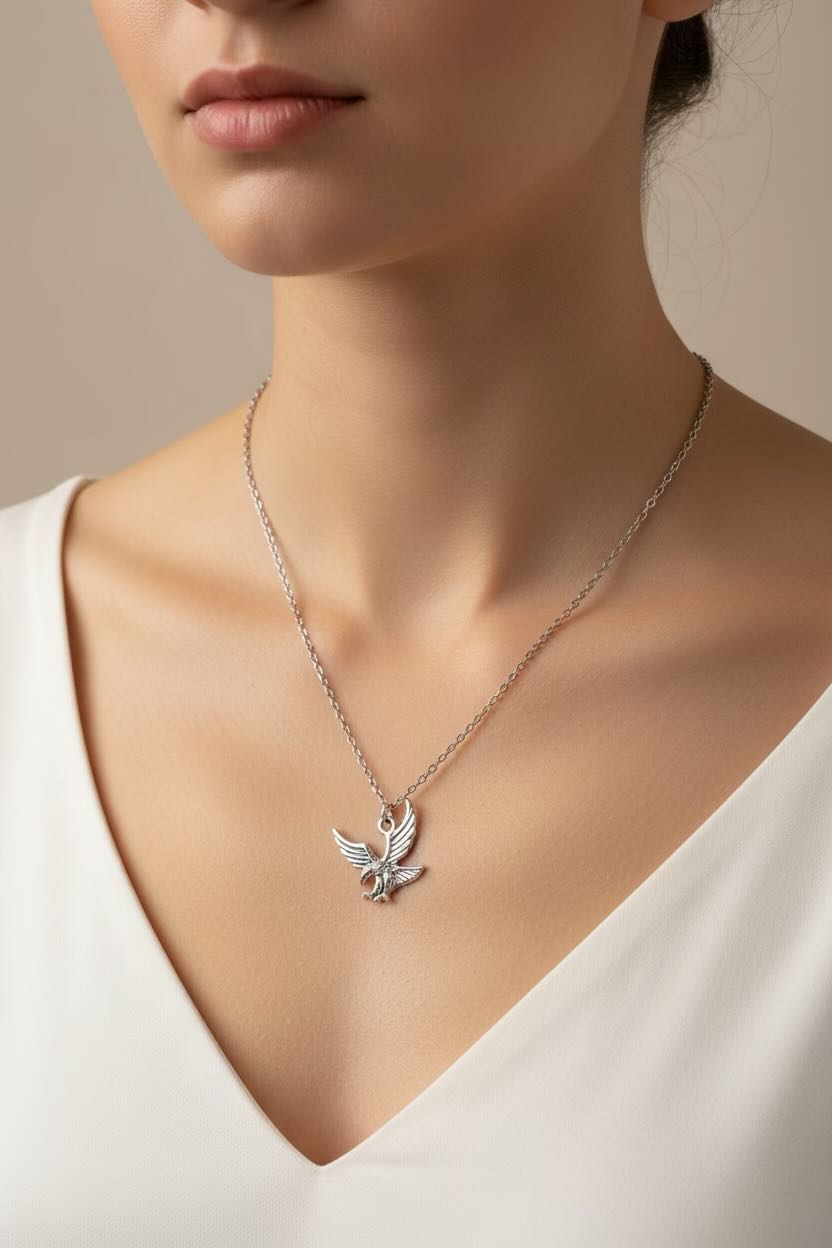 Necklace with a eagle pendant worn by a person in a white dress.