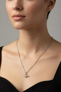 Close-up of a woman wearing a delicate necklace with a small pendant against a neutral background