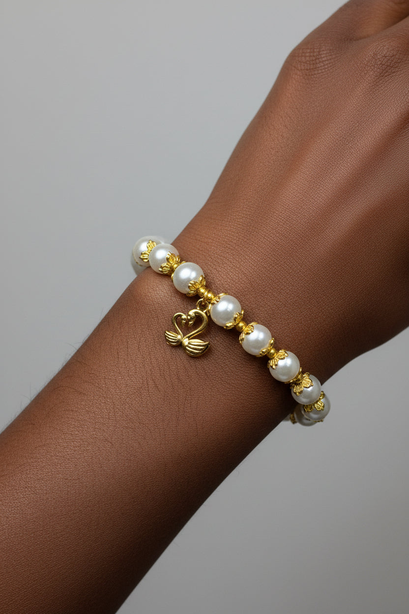 A gold and white pearl bracelet displayed on a model's wrist.