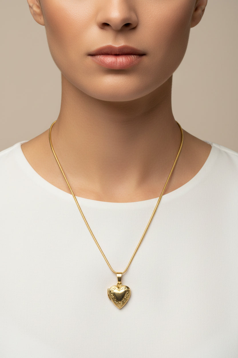 Gold brass heart-shaped locket on a stainless steel snake chain necklace on a model