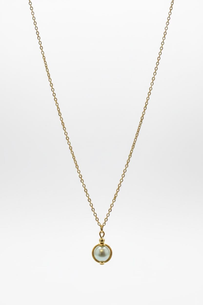 A delicate gold chain necklace featuring a small round bezel-set aqua blue pearl pendant, displayed against a clean white background.