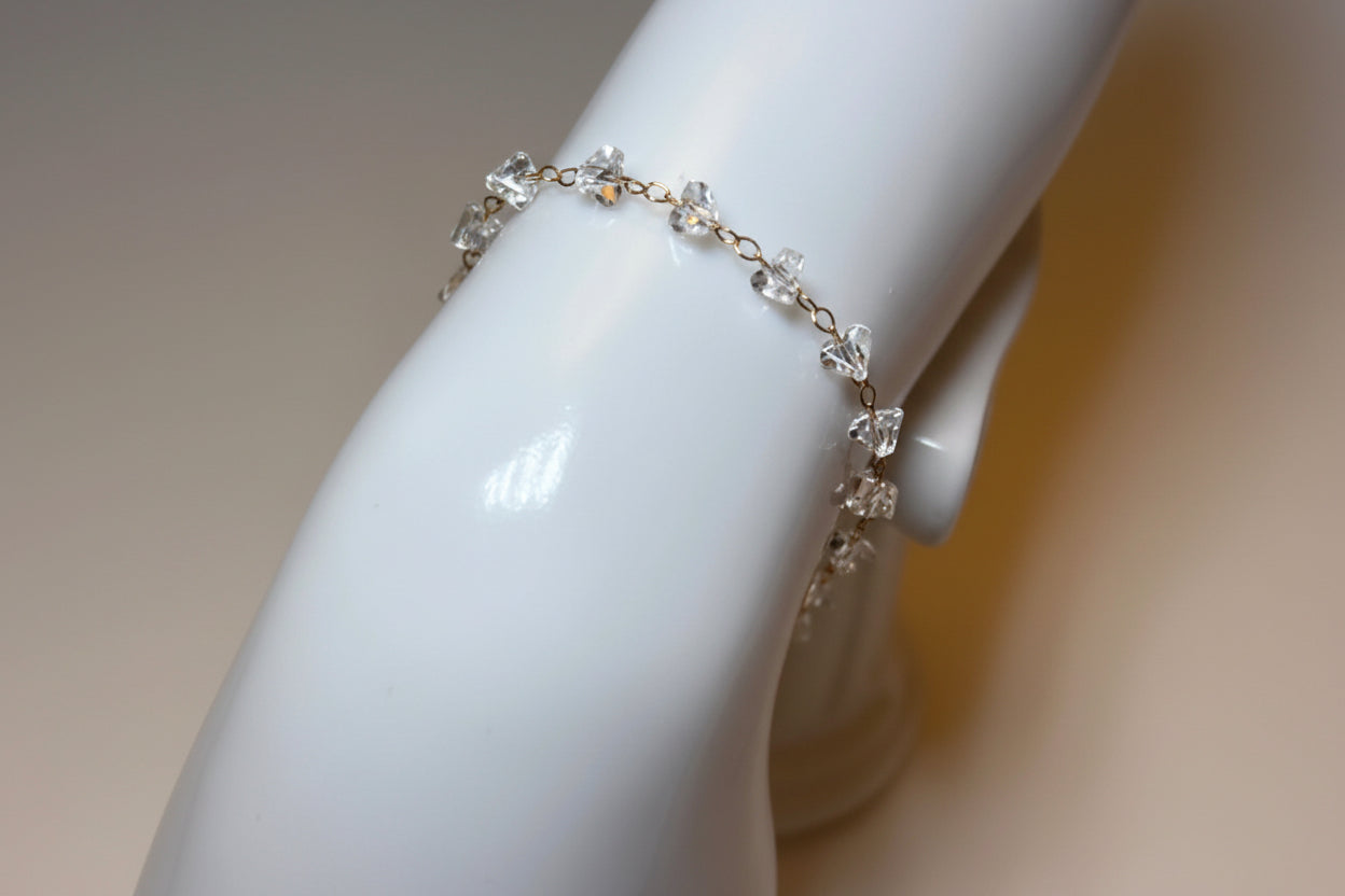 Delicate silver bracelet on a white mannequin arm against a neutral background