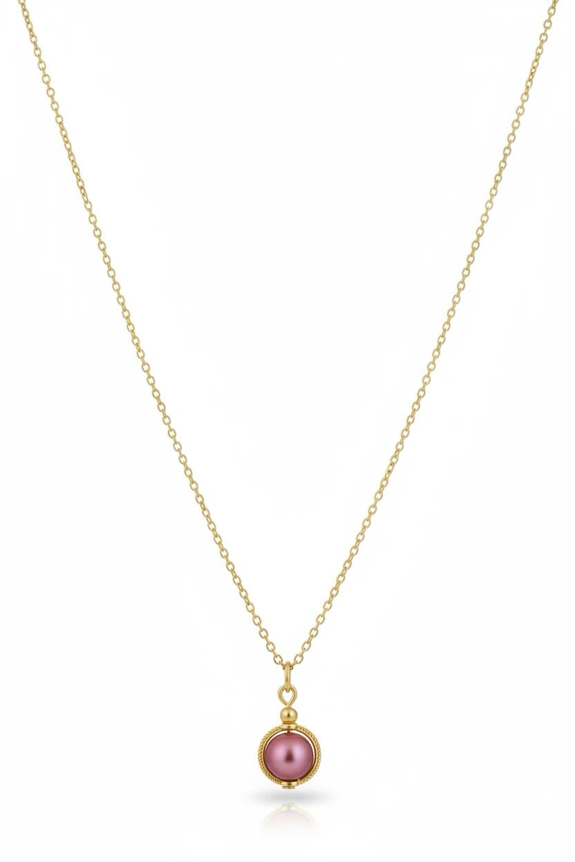 A delicate gold chain necklace featuring a small circular pendant with a cherry red pearl, displayed against a clean white background.