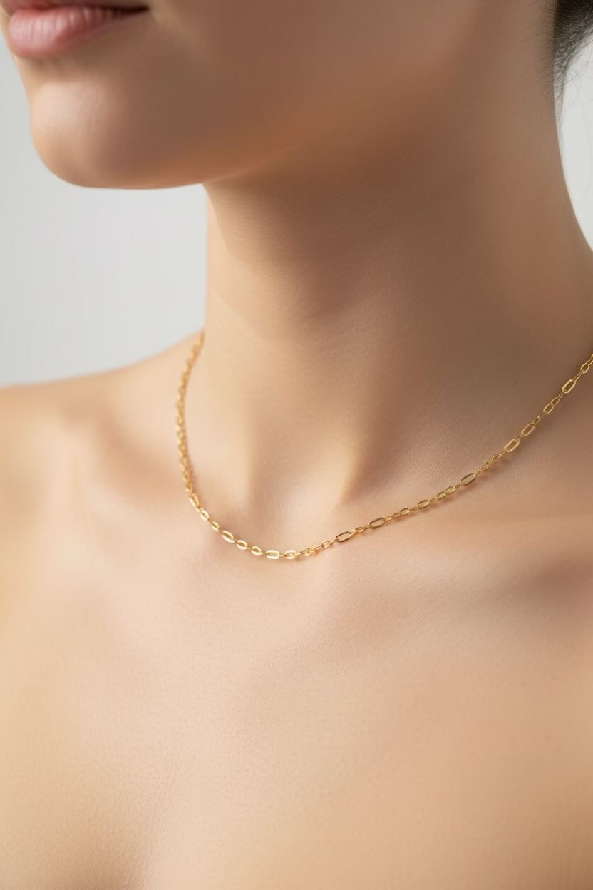 Gold necklace on a person's neck against a neutral background