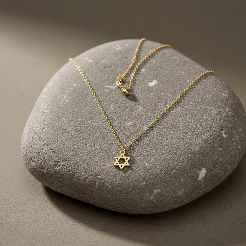 Gold necklace with a Star of David pendant on a light gray background