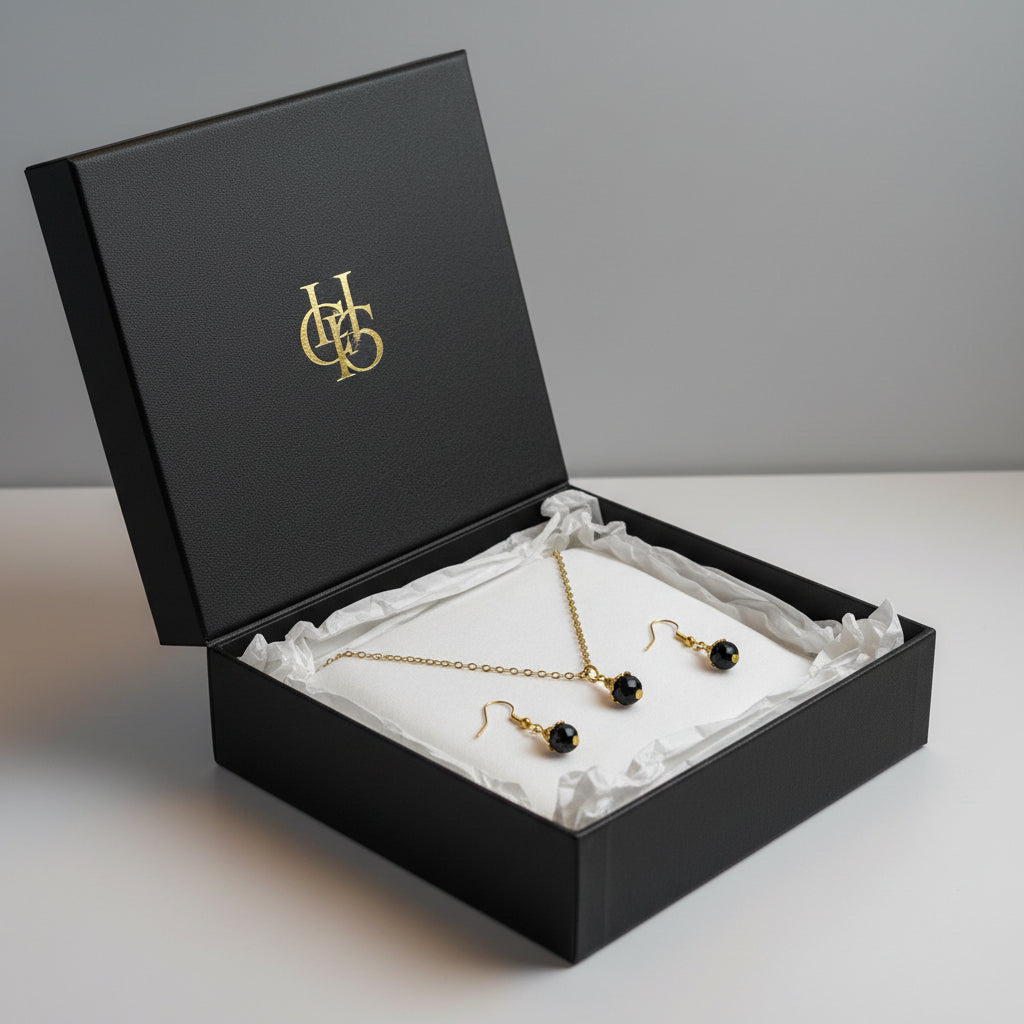 Gold-tone necklace and matching drop earrings displayed in a black gift box.