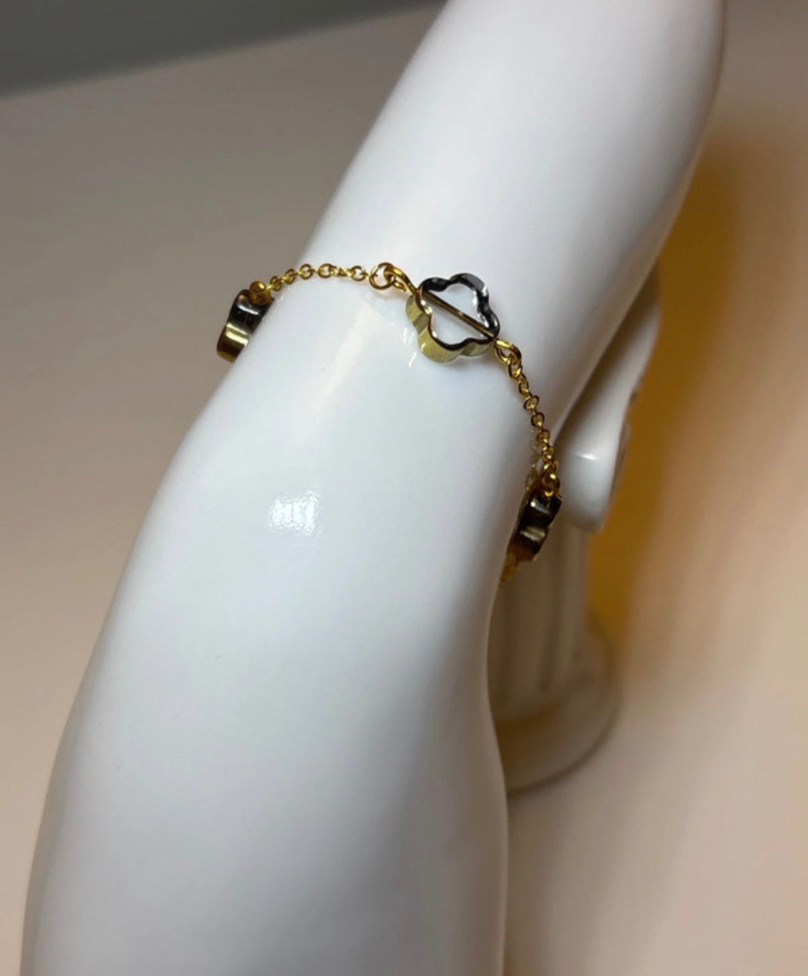 Gold chain clover bracelet on a white mannequin arm