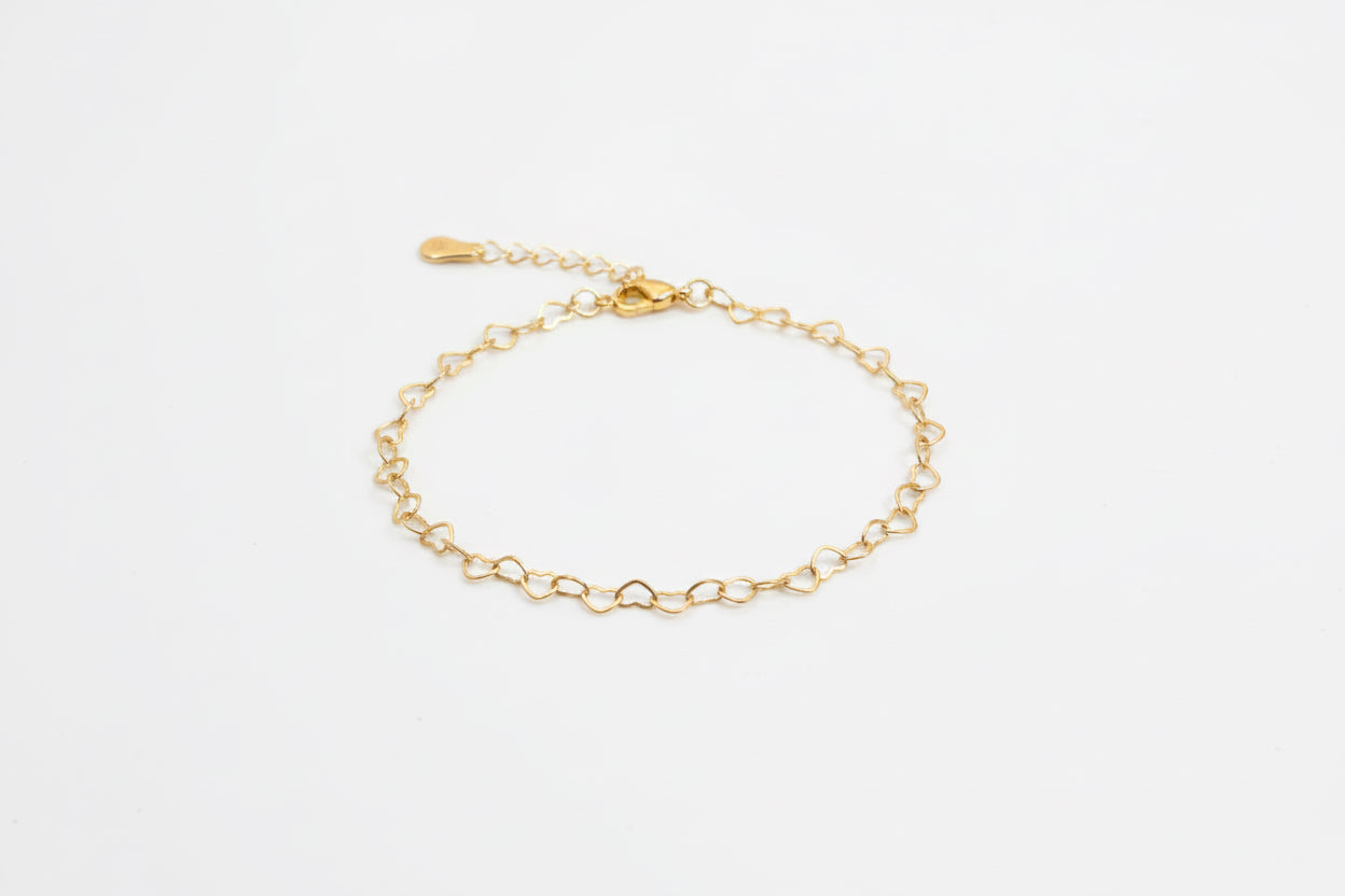 Gold chain bracelet on a white surfacel background
