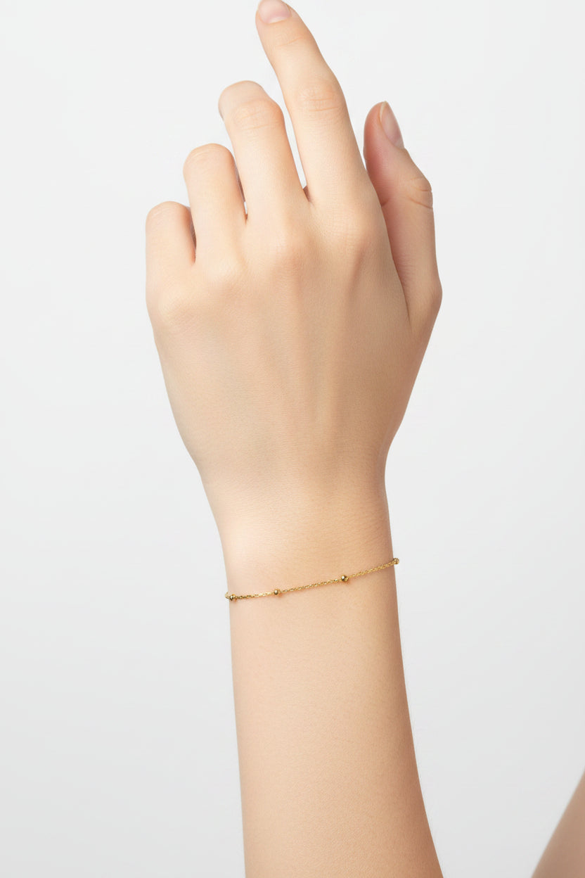 Gold delicate ball chain on a model's arm