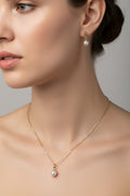 A gold chain pearl necklace and matching stud earrings on a model.