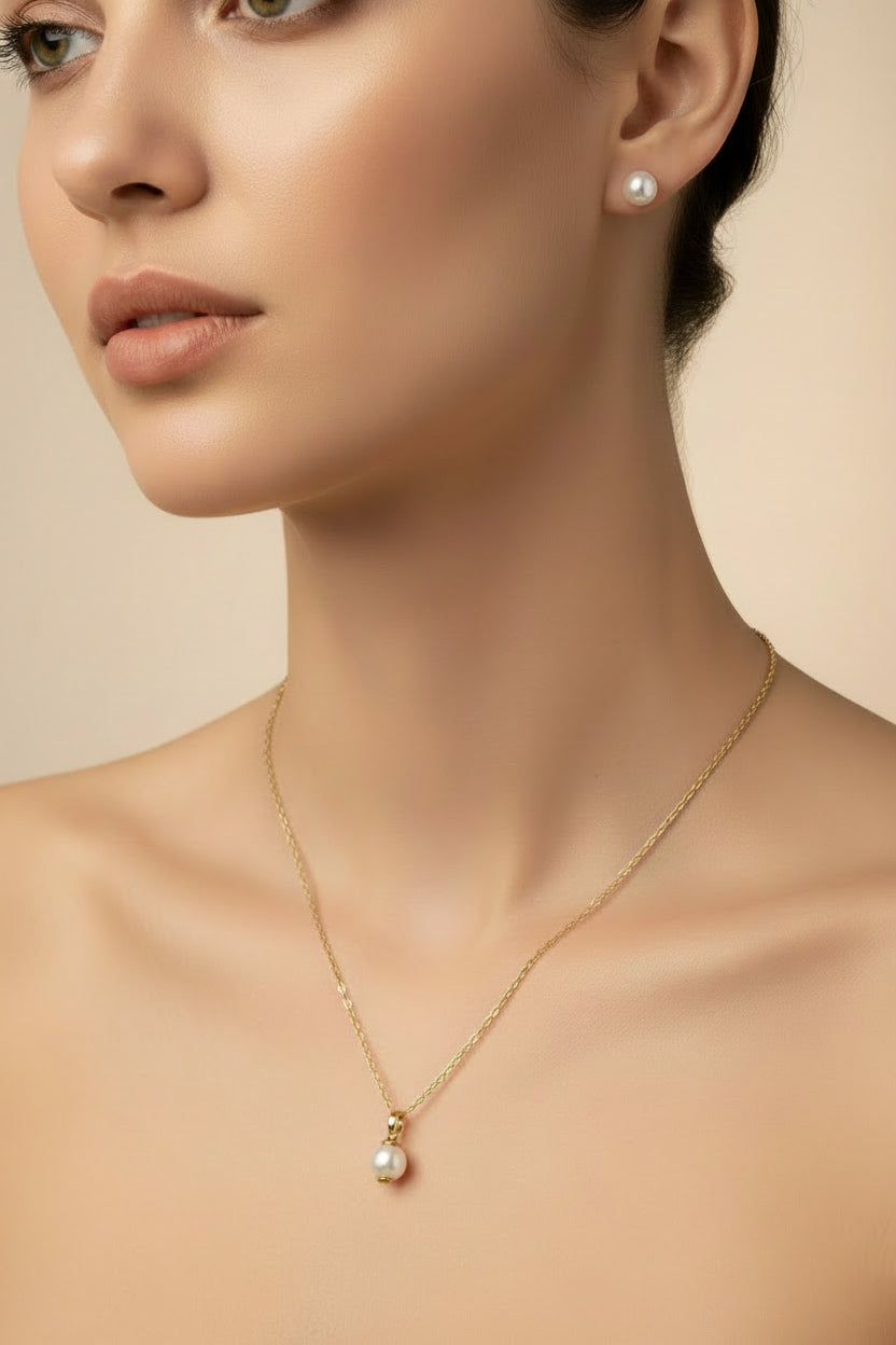 A gold chain necklace and matching stud earrings on a model.