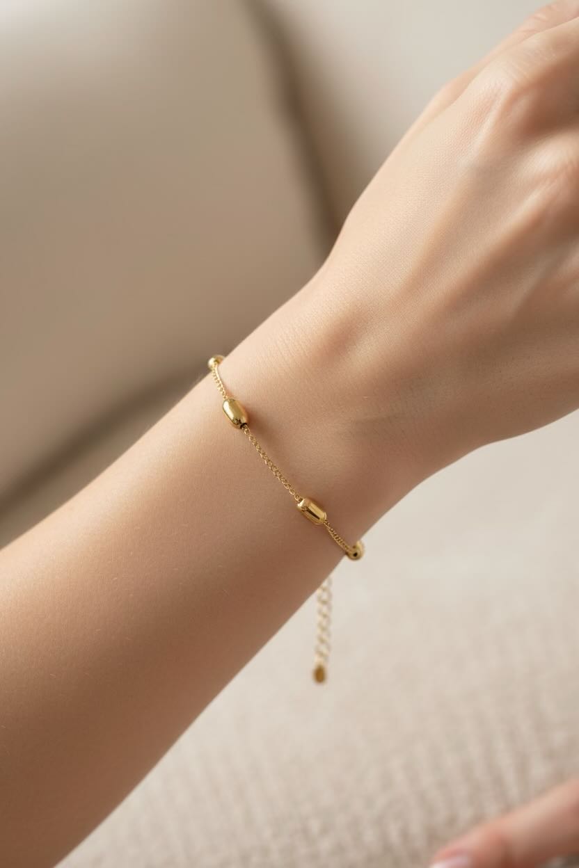 Gold bracelet on a wrist against a neutral background
