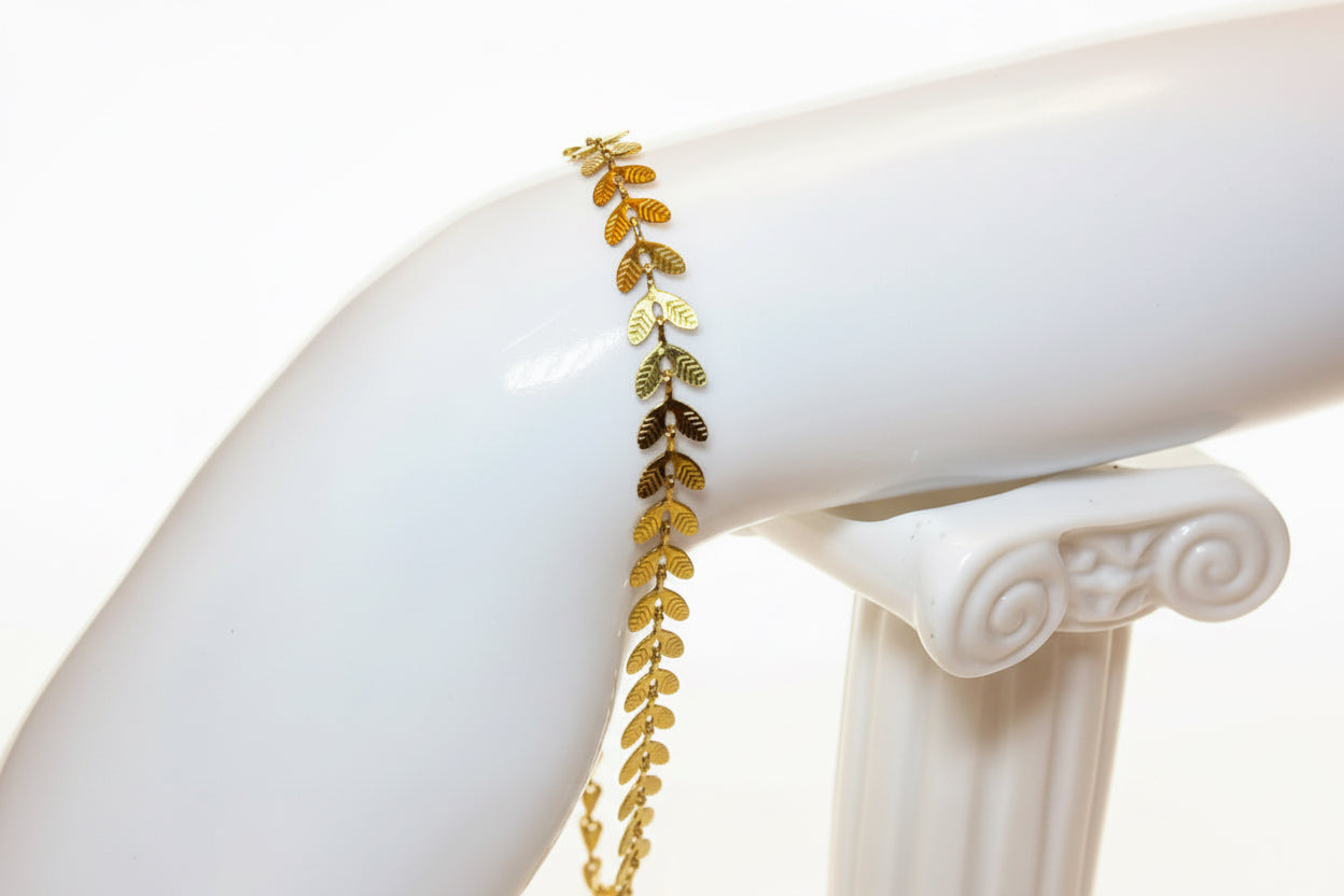 Gold leaf bracelet on a white mannequin arm against a white background