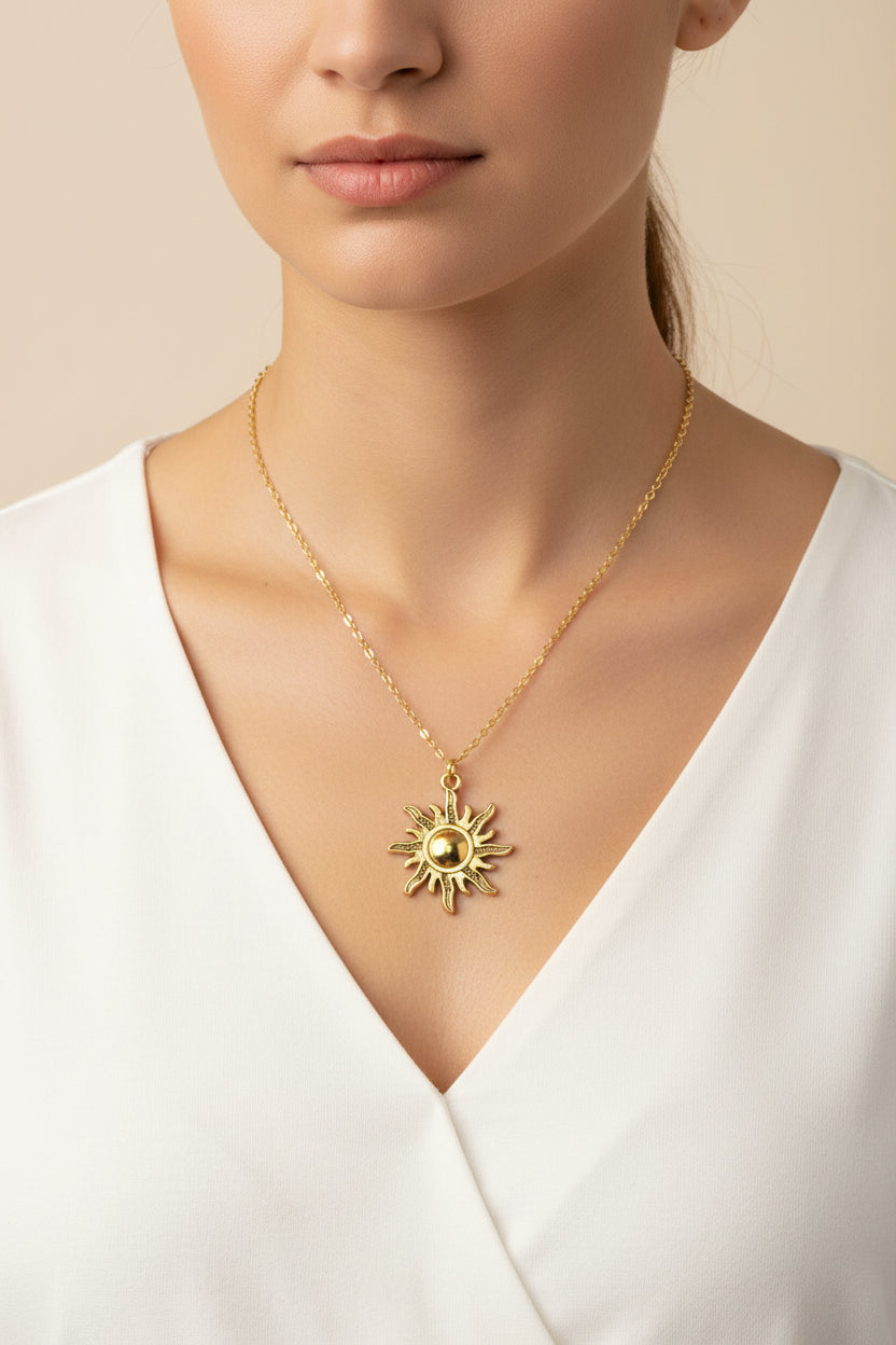 A gold-toned sun pendant necklace displayed on a model