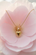Gold brass heart-shaped locket on a stainless steel necklace on a large petal