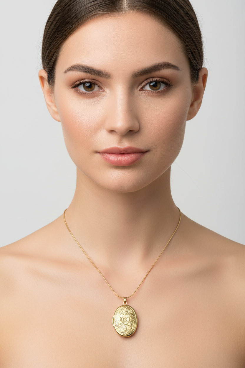 An oval gold pendant necklace with an embossed floral pattern, displayed on a white ceramic jewelry bust against a neutral background.