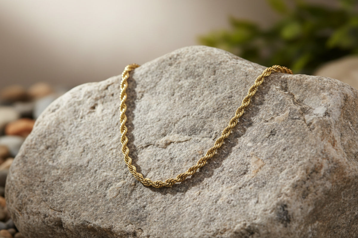 A gold-toned twisted rope chain necklace displayed on a white mannequin bust.