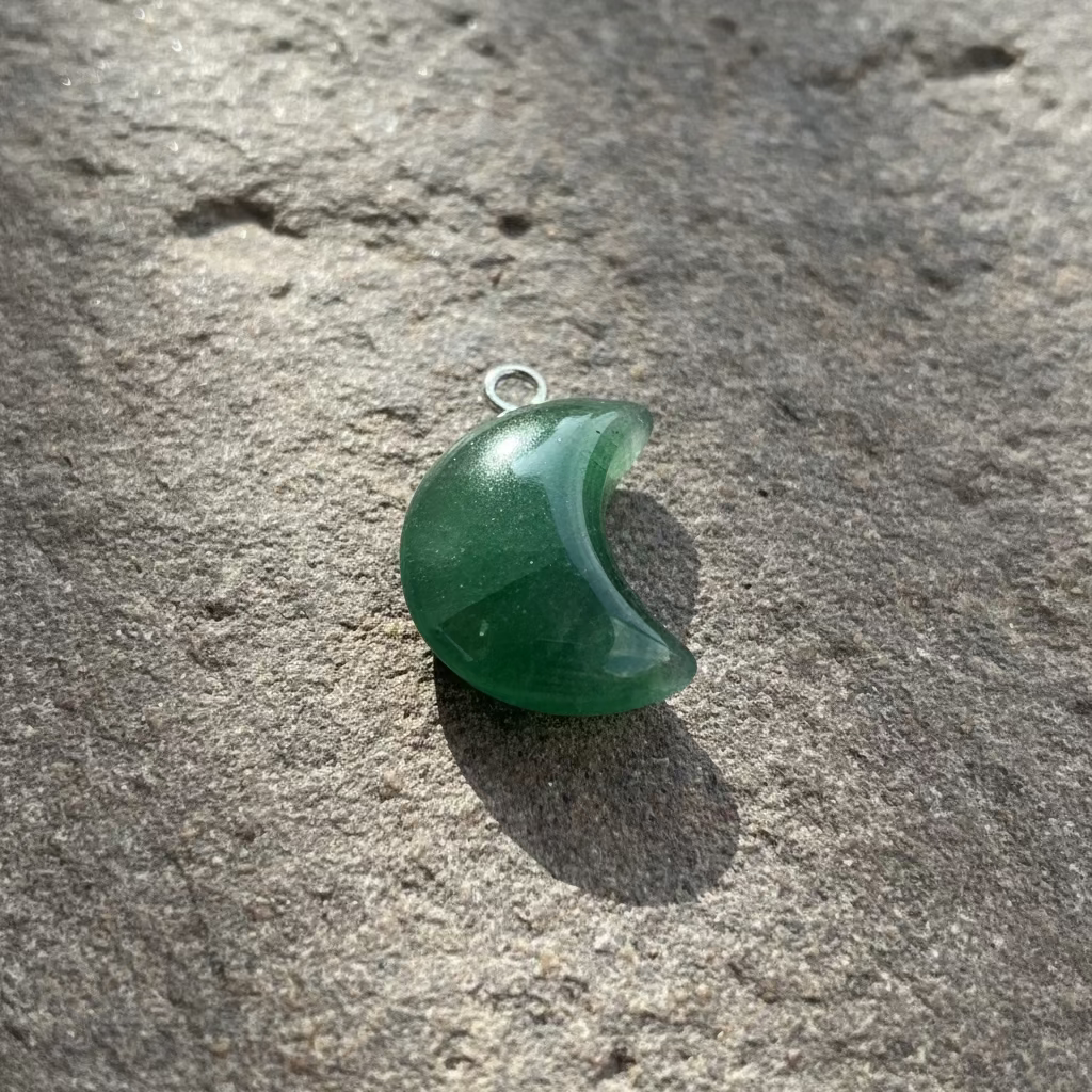 Green crescent-shaped pendant on a light gray background