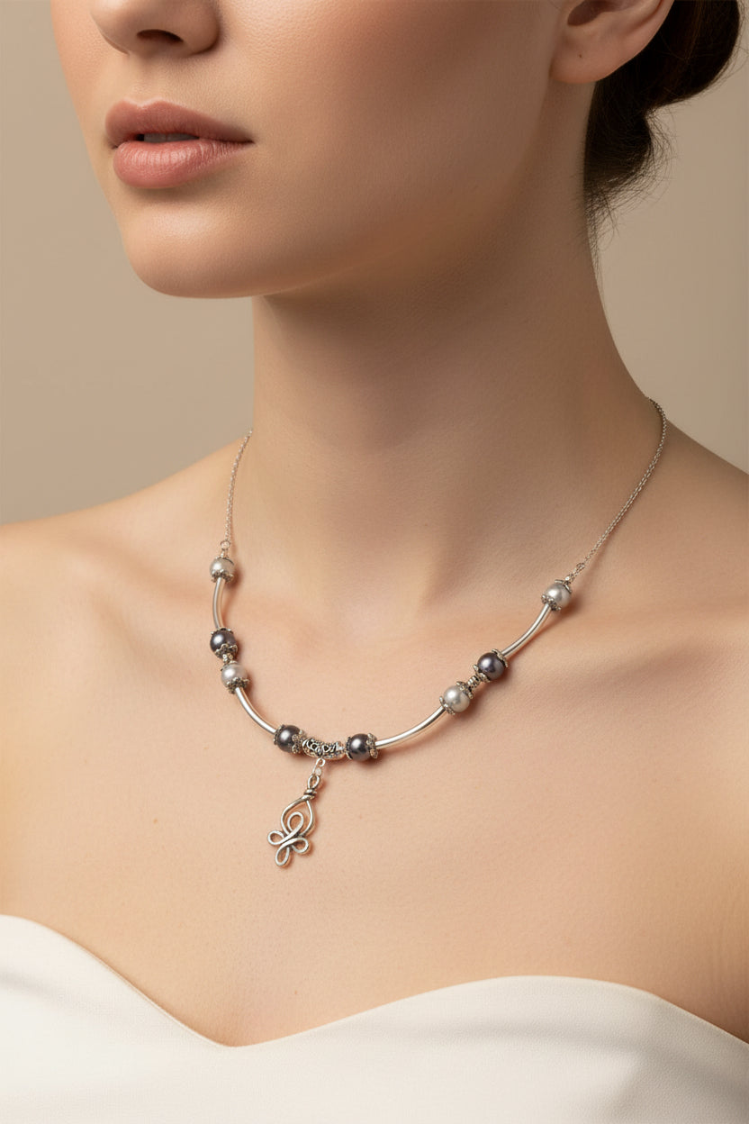 Necklace with beads and a charm on a model against a neutral background