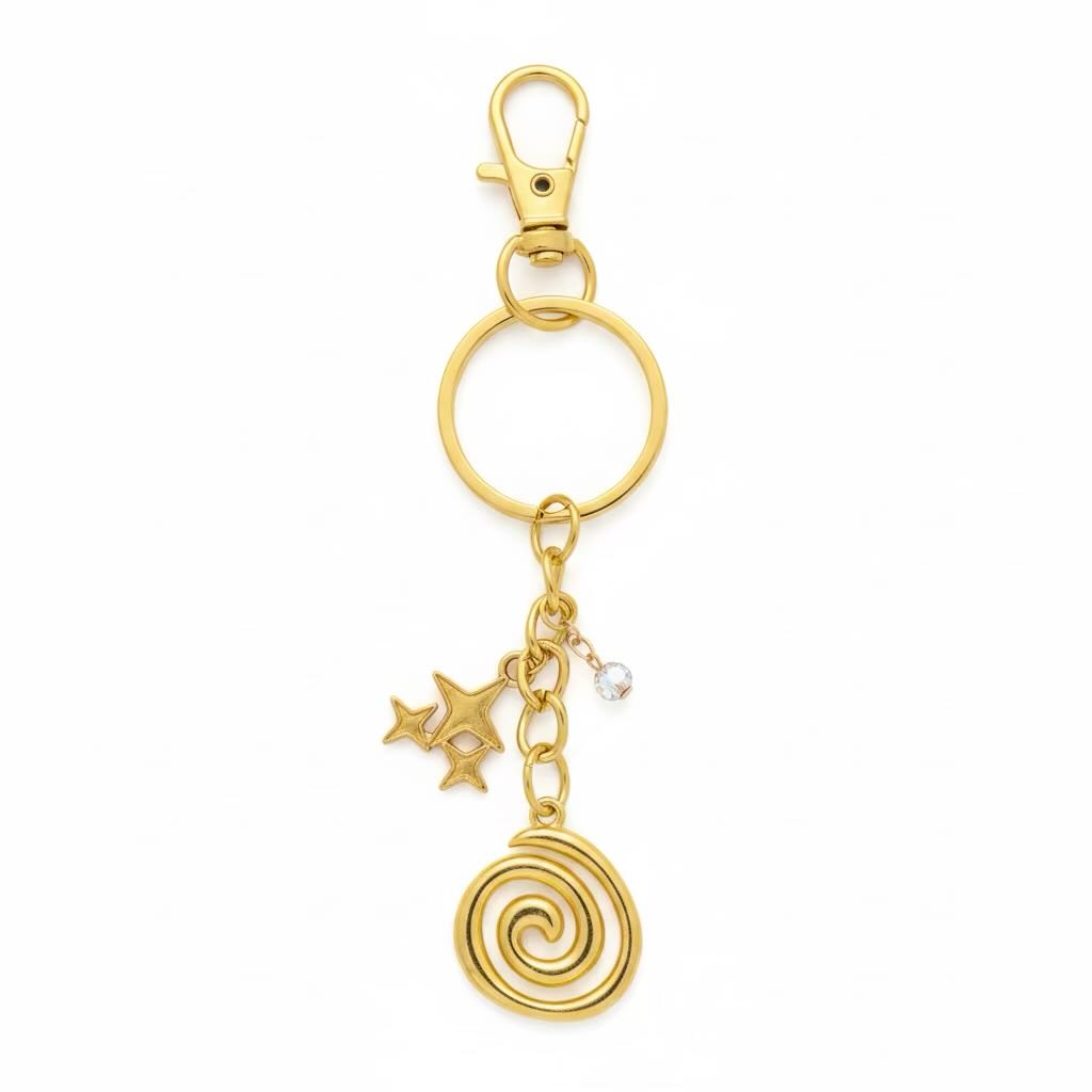 Gold-toned metal keyring with a lobster clasp, split ring, three star charms, a small clear rhinestone, and a spiral charm on a white background.